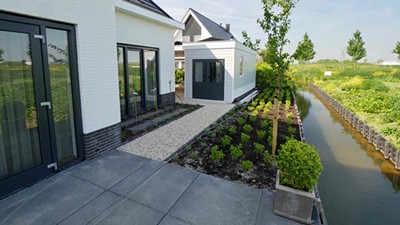 Zijaanzicht van tuin met beplanting, bestrating en grindpad